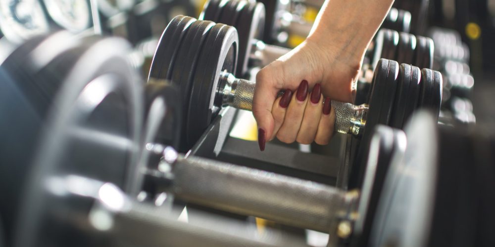 Close up of woman's hand holding dumbbell in gym.